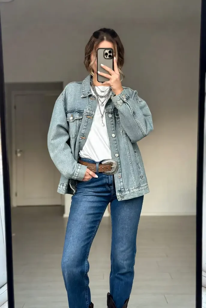 A casual 18th birthday outfit idea: denim-on-denim look with a brown western statement belt and silver layered necklaces.