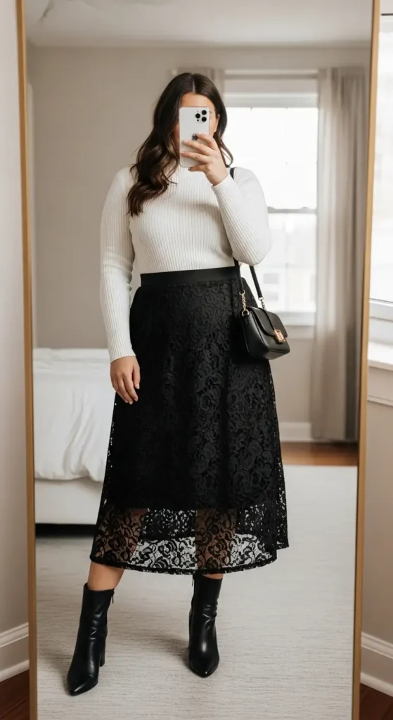 Plus size black lace skirt outfit with a white ribbed turtleneck, black bag, and ankle boots

