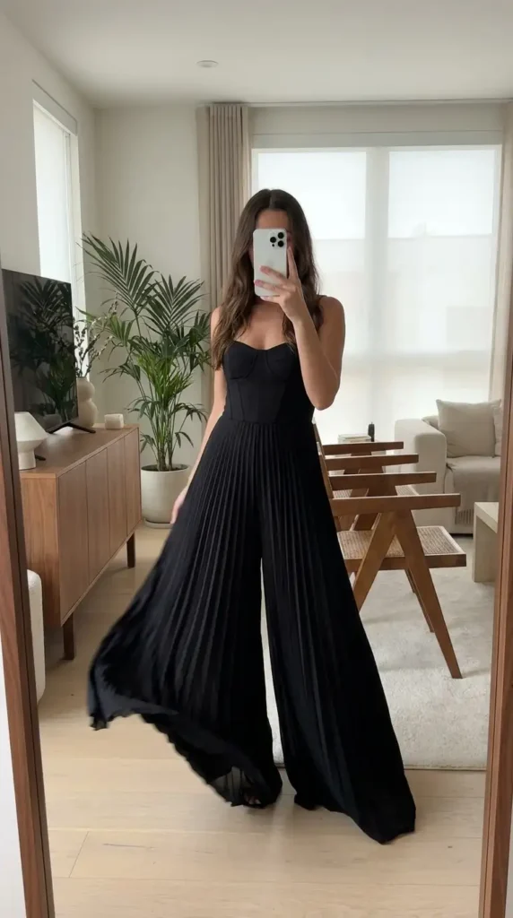 Black classy wedding guest jumpsuit summer with strapless corset and flowing pleated wide legs.
