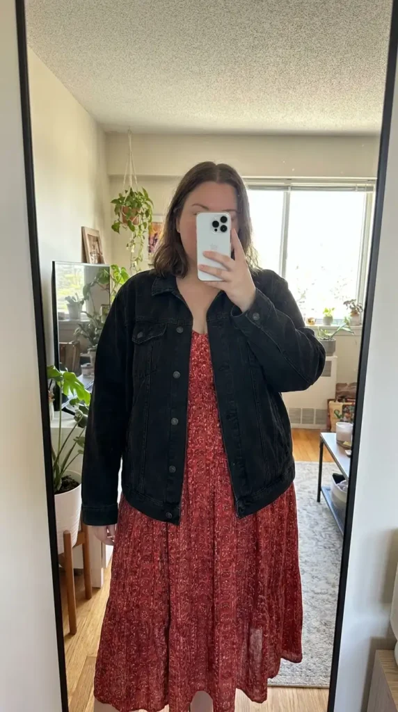 Red and black outfit ideas for plus size: oversized black denim jacket layered over a red floral midi sundress.
