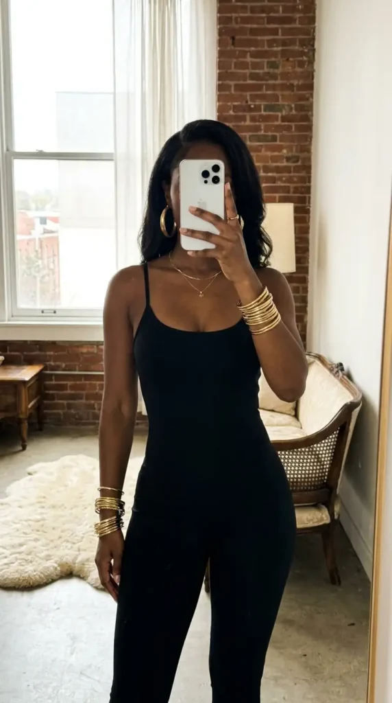 Sleek black jumpsuit accented with multiple gold accessories, showcasing black and gold outfit ideas for black women