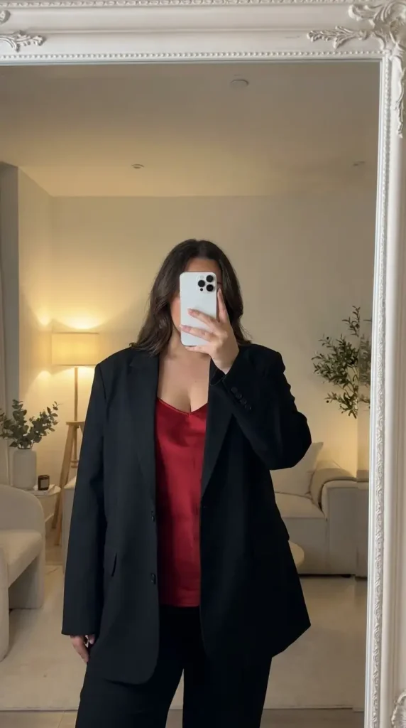 Red and black outfit ideas for plus size: oversized black blazer over a red satin camisole with black trousers.
