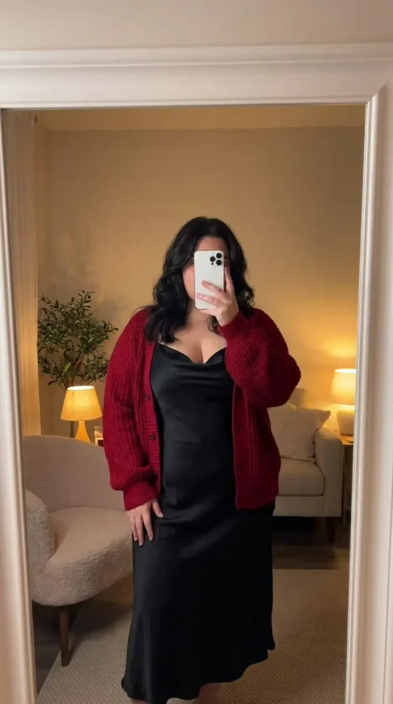 Red and black outfit ideas for plus size: black satin slip dress layered under a chunky red knit cardigan.
