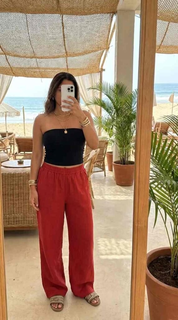 Beachside red & black summer outfits: black bandeau tube top with wide-leg red linen pants and slide sandals
