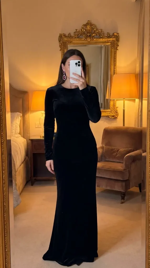 Floor-length black velvet gown with red gemstone drop earrings, an elegant red and black outfit idea for party.
