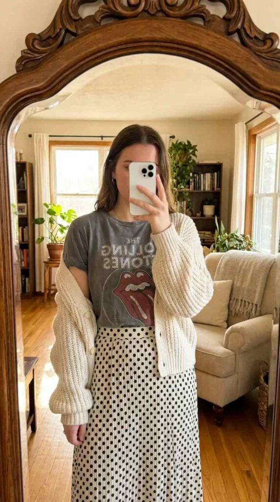 Black and white polka dot skirt outfits with a vintage graphic tee layered under a cream knit cardigan
