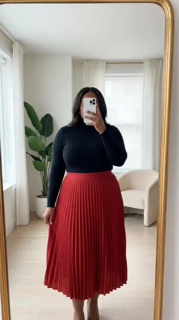 Red and black outfit ideas for plus size: black fitted turtleneck tucked into a red pleated midi skirt with heels.

