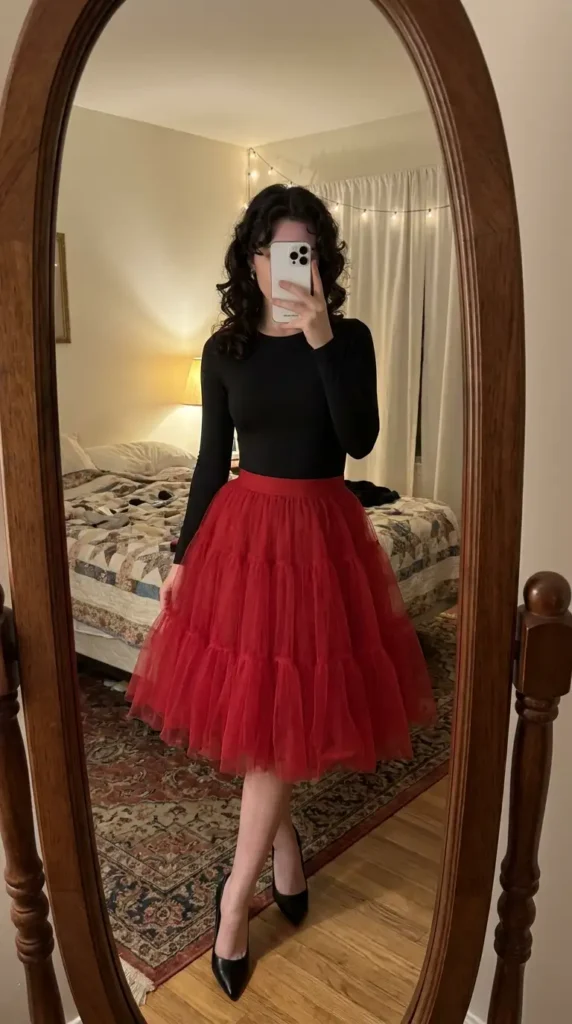 Voluminous red tulle skirt paired with a black long-sleeve bodysuit, a festive red and black outfit idea for party.
