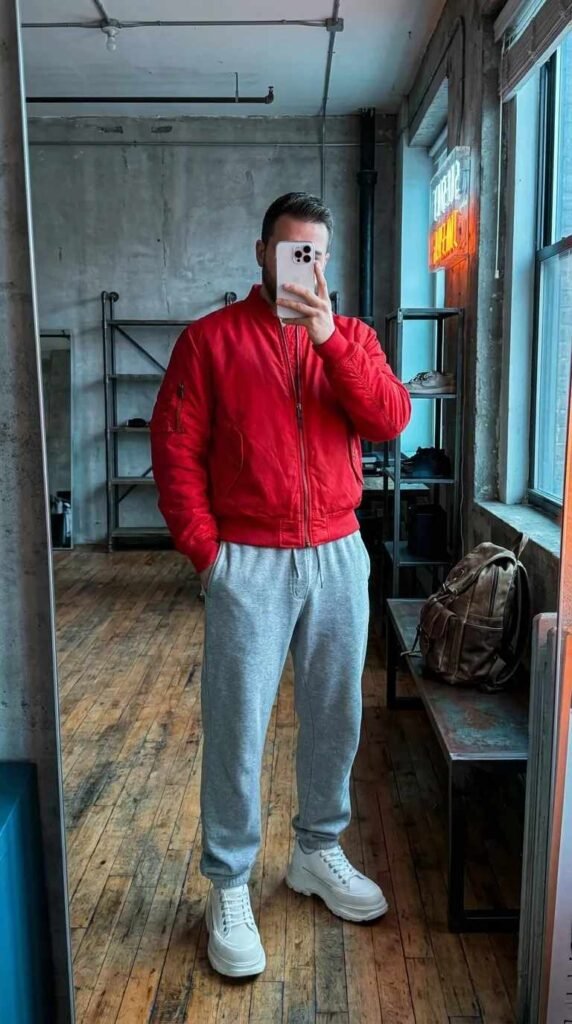 Man in red bomber jacket and grey sweatpants mirror selfie from 20 Red Outfit Ideas for Men That Actually Slay