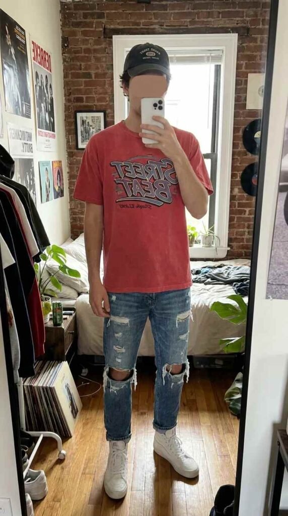 Man in red graphic tee and ripped jeans bedroom mirror selfie from 20 Red Outfit Ideas for Men That Actually Slay