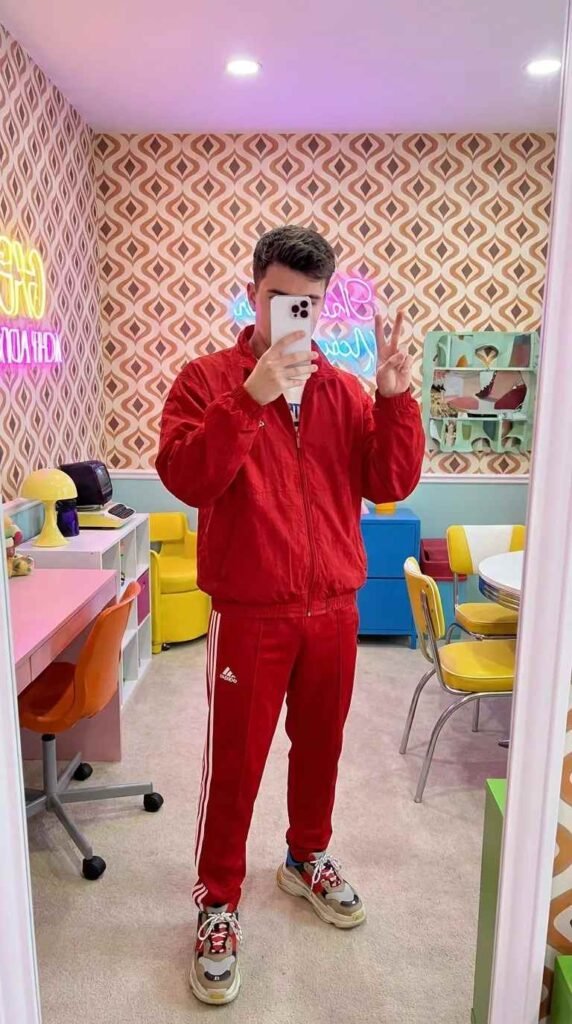 Man in red Adidas tracksuit making peace sign in colorful room from 20 Red Outfit Ideas for Men That Actually Slay