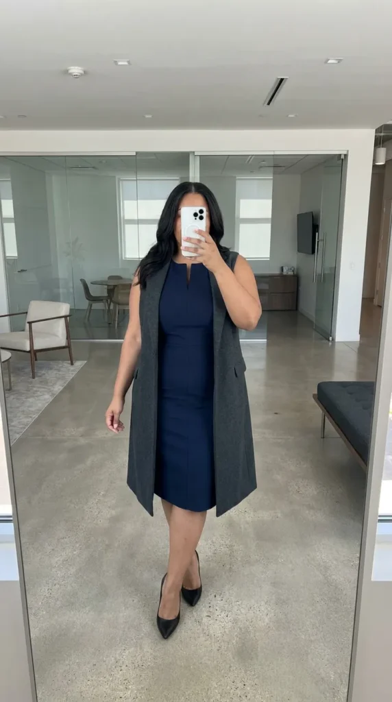 Plus-size woman in navy sheath dress and long vest as business casual outfit ideas for plus size women.